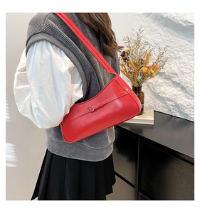 Detailed view of the red leather shoulder bag worn under the arm by a female model