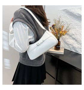 Close-up of minimalist white leather underarm bag with metal buckle detail on a model
