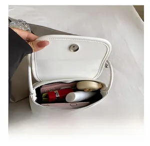Interior view of small white leather crossbody bag showing phone and cosmetics storage