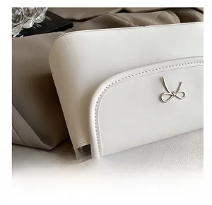 Detailed close-up of a white leather crossbody bag featuring a silver metal bow buckle