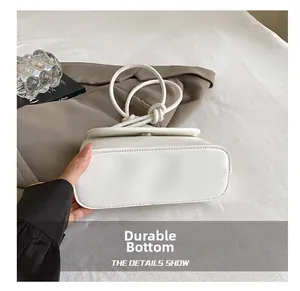 Detail shot of the durable oval bottom and fine stitching on the white leather handbag
