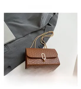 Detail view of brown woven texture bag with gold U-shaped lock and chain strap