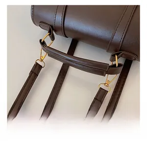 Close-up of the comfortable dark brown litchi grain leather handle with gold hardware