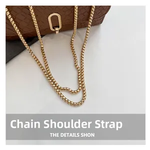 Close-up of golden chain strap and embossed brown leather texture on a square bag