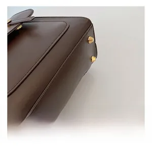 Detail of dark brown leather handbag base featuring four protective gold metal feet