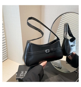 Detail of minimalist black patent leather underarm bag with silver buckle and sleek strap