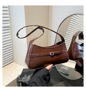 Detail of minimalist chocolate brown shoulder bag with silver buckle in aesthetic setting