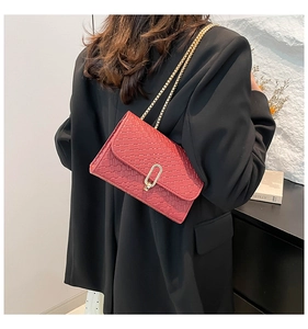 Detail of red woven texture crossbody bag with gold chain strap on a model