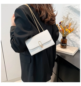 Detail of white crocodile pattern flap bag featuring gold chain strap and U-shaped lock