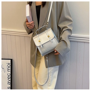 Detail of silver crossbody bag with gold round buckles and metallic leather finish