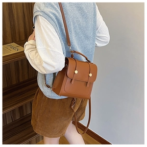 Side view of a vintage brown PU leather backpack with gold buckle on a model