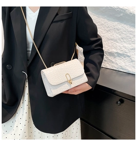 Detail showing the white textured crossbody bag with gold rectangular clasp and chain strap