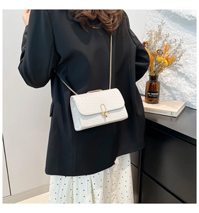 Sac bandoulière tressé blanc avec chaîne dorée porté par un mannequin en style de bureau
