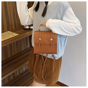 Close-up of a brown PU leather vintage backpack with metal buckles and top handle