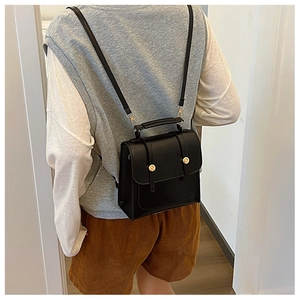 Detail of black PU leather backpack with golden round buckle and top handle feature
