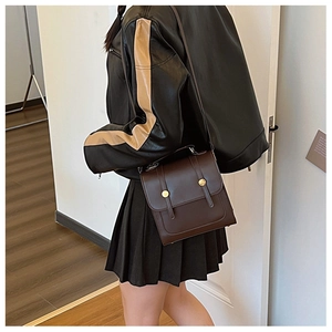 Detail of dark brown vintage messenger bag with gold buckles on female model