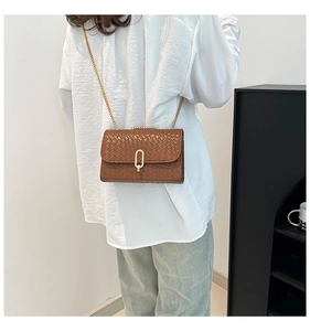 Detailed view of brown woven texture and gold metal buckle on a stylish crossbody bag