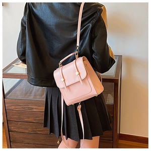 Close-up of pink matte PU leather backpack featuring golden metal buckles on black jacket