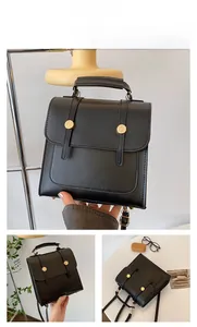 Detail of a vintage black leather backpack with square flap and golden snap buttons