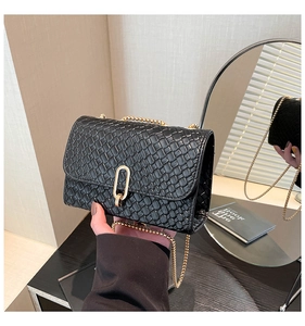 Détail du sac à main en cuir tressé noir avec chaîne dorée et fermoir pivotant
