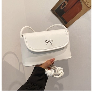 Detail of white PU leather crossbody bag with metal bow and braided rope strap