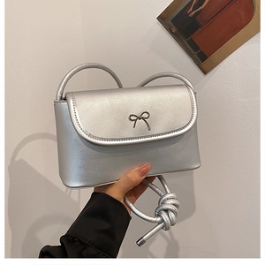 Detail of silver crossbody bag featuring metallic PU texture and a bow metal buckle