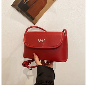 Detail of red square crossbody bag with silver bow buckle and twisted rope strap