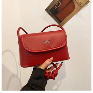 Close-up of red leather handbag with silver metal bow and knotted rope strap detail