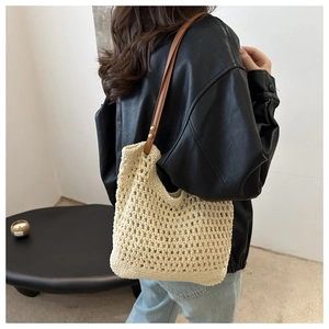 Detail of beige crochet tote bag with brown leather strap and gold rivet accents