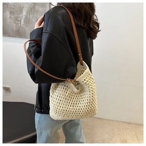 Detail of hand-woven cotton mesh tote bag with brown faux leather strap and metal rivets