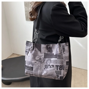 Detail of graffiti tote bag with newspaper print and stylish metal chain strap