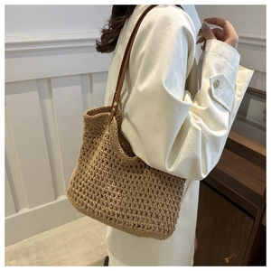 Close-up of khaki crochet tote bag with brown leather handles and metal rivets