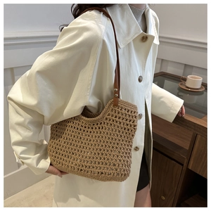 Detail of woven straw shoulder bag featuring hollow crochet texture and leather straps