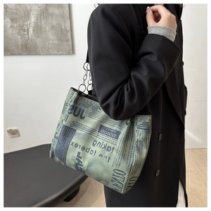 Close-up of vintage newspaper print tote bag with black chain strap on model