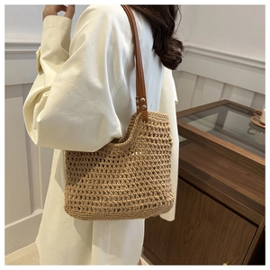 Detail of hand-woven mesh beach tote with brown leather strap and rivet accents