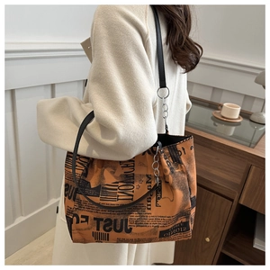 Detail of orange tote bag with black street style lettering and silver metal ring
