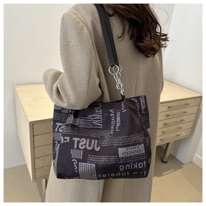 Detail of newspaper print tote bag showing silver metal chain rings and large capacity