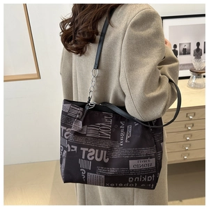 Detail of trendy tote bag featuring newspaper print fabric and silver chain strap accents