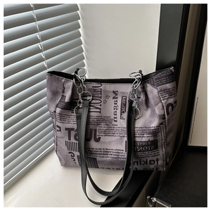 Close-up of retro newspaper print tote bag with silver chain and black leather handles