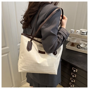 Détail d'un sac cabas bicolore minimaliste en cuir blanc cassé avec bandoulières marron