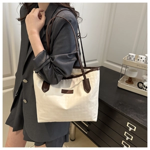 Vue portée épaule d'un grand sac cabas bicolore crème et marron avec logo de mode