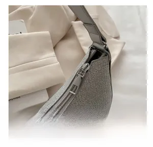 Close-up of smooth silver zipper on a textured woven metallic shoulder bag
