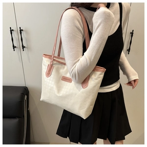Détail du cabas en cuir texturé crème avec poignées roses et étiquette de mode