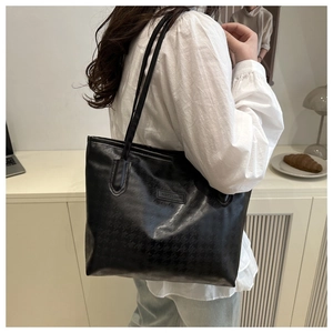 Détail du sac cabas noir avec motif pied-de-poule texturé et plaque de logo en métal