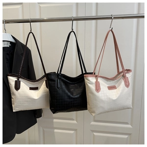 Détail de sacs cabas à texture pied-de-poule avec plaques de logo métalliques