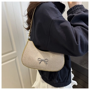 Detail of champagne gold hobo bag with silver bow accent worn by model in home setting