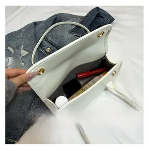 Détail du sac bandoulière en cuir blanc montrant l'intérieur spacieux et le fermoir doré
