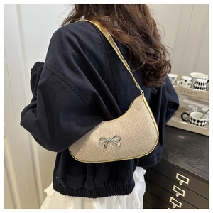 Detail view of champagne glitter underarm bag featuring a silver metal bow accent