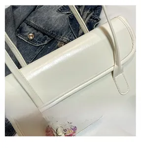 Détails d'un sac baguette blanc brillant avec rabat et accessoires décoratifs sur le côté