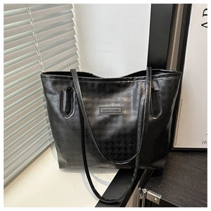 Gros plan sur la texture pied-de-poule et l'étiquette en cuir du sac cabas noir
